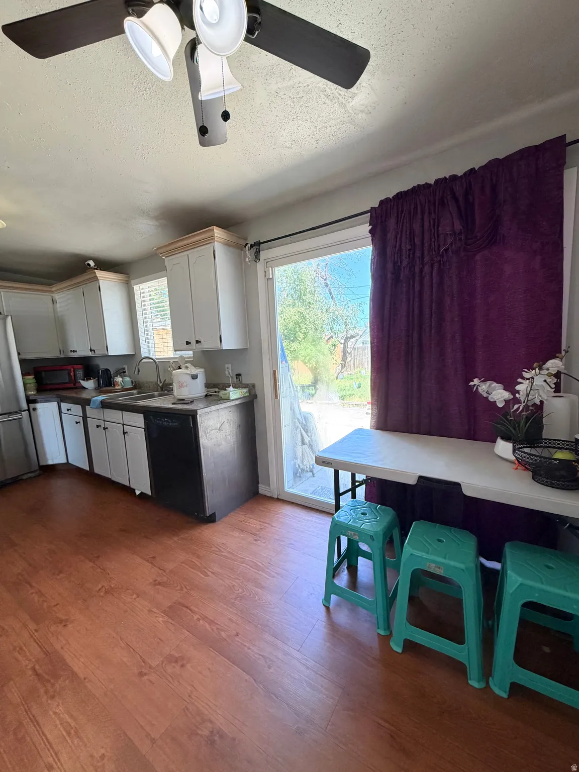 Kitchen area with wood-finish flooring, white cabinetry, and a ceiling fan with integrated lighting