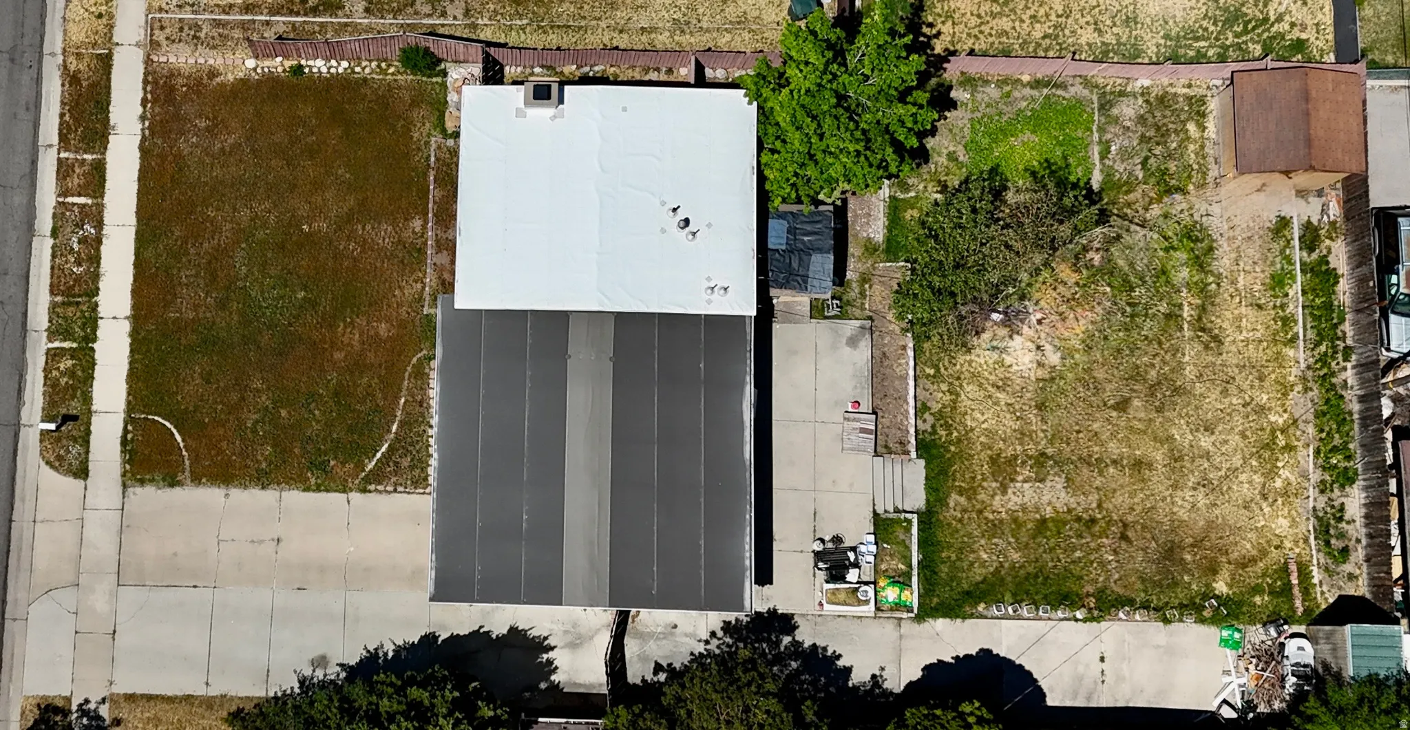 Spacious lot featuring a commercial building with a light-colored flat roof and an adjacent dark-colored flat roof section
