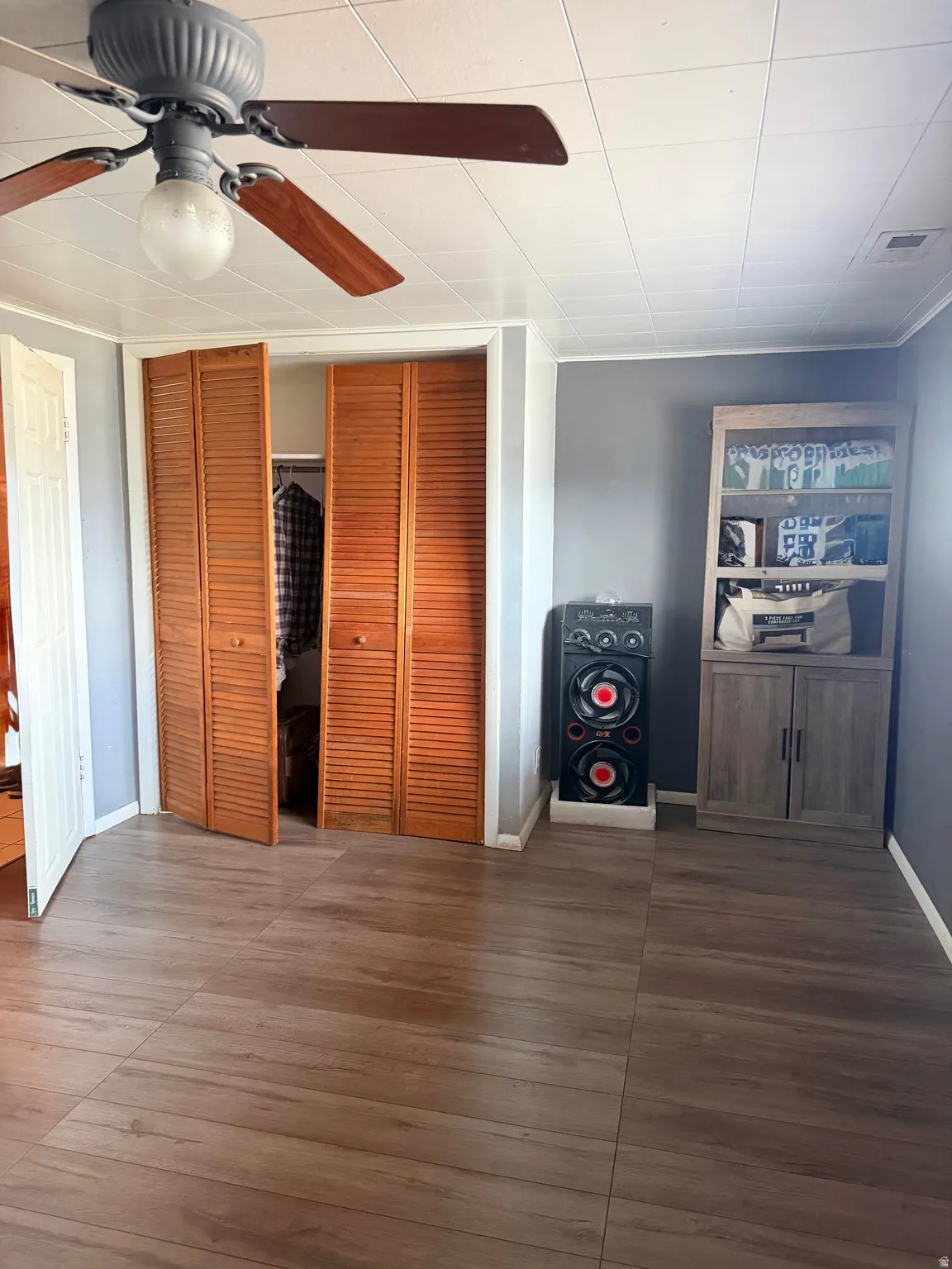 Spacious room featuring laminate wood-finish flooring, a ceiling fan with integrated lighting, and a closet with bi-fold louvered doors