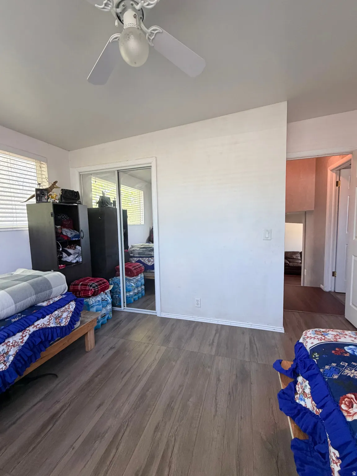 Interior room featuring laminate wood-finish flooring, white walls, and a ceiling fan