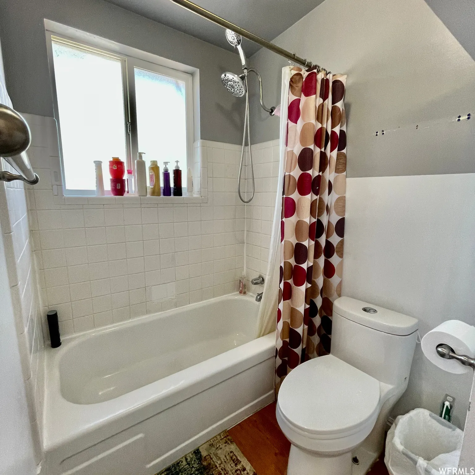 Bathroom featuring a white tub, white tiled surround, and a window for natural light