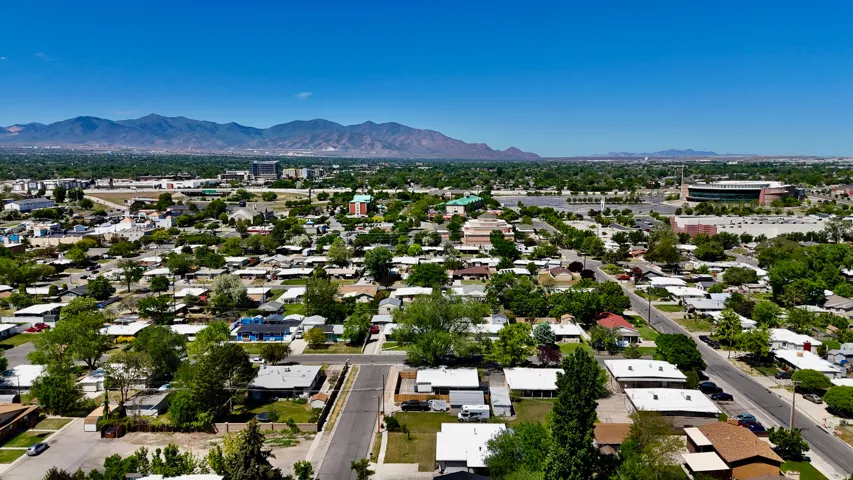 Expansive aerial perspective showcasing a neighborhood with mature trees and mountain scenery in the background