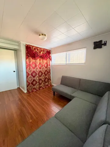 Room featuring laminate wood-finish flooring, a rectangular window with blinds, and a flush mount ceiling light