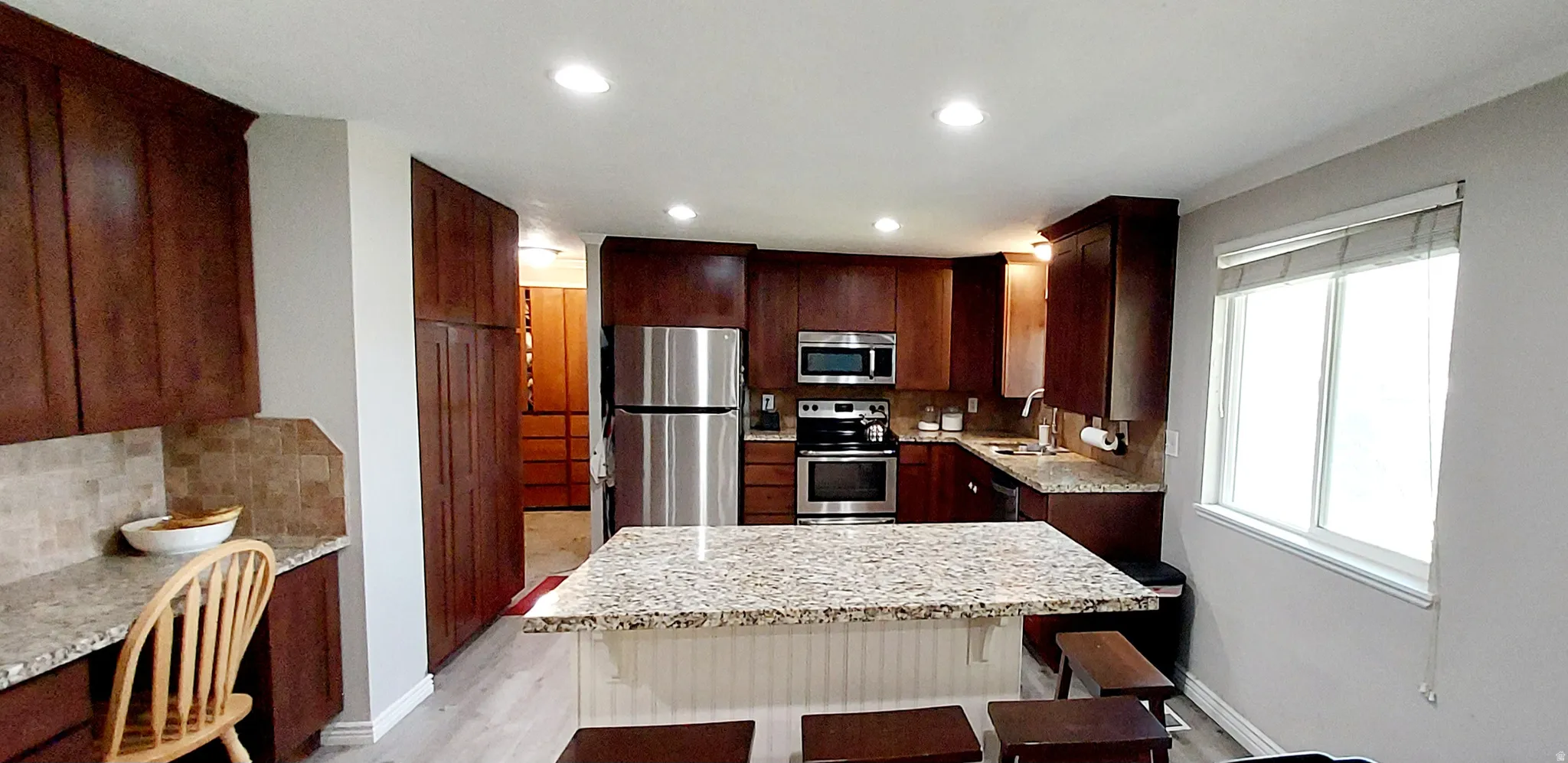 Kitchen with stainless steel appliances, light stone counters, recessed lighting, a breakfast bar area, and tasteful backsplash