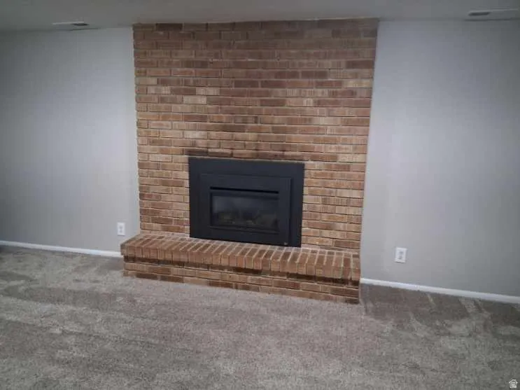 Detailed view of carpet floors and a brick fireplace
