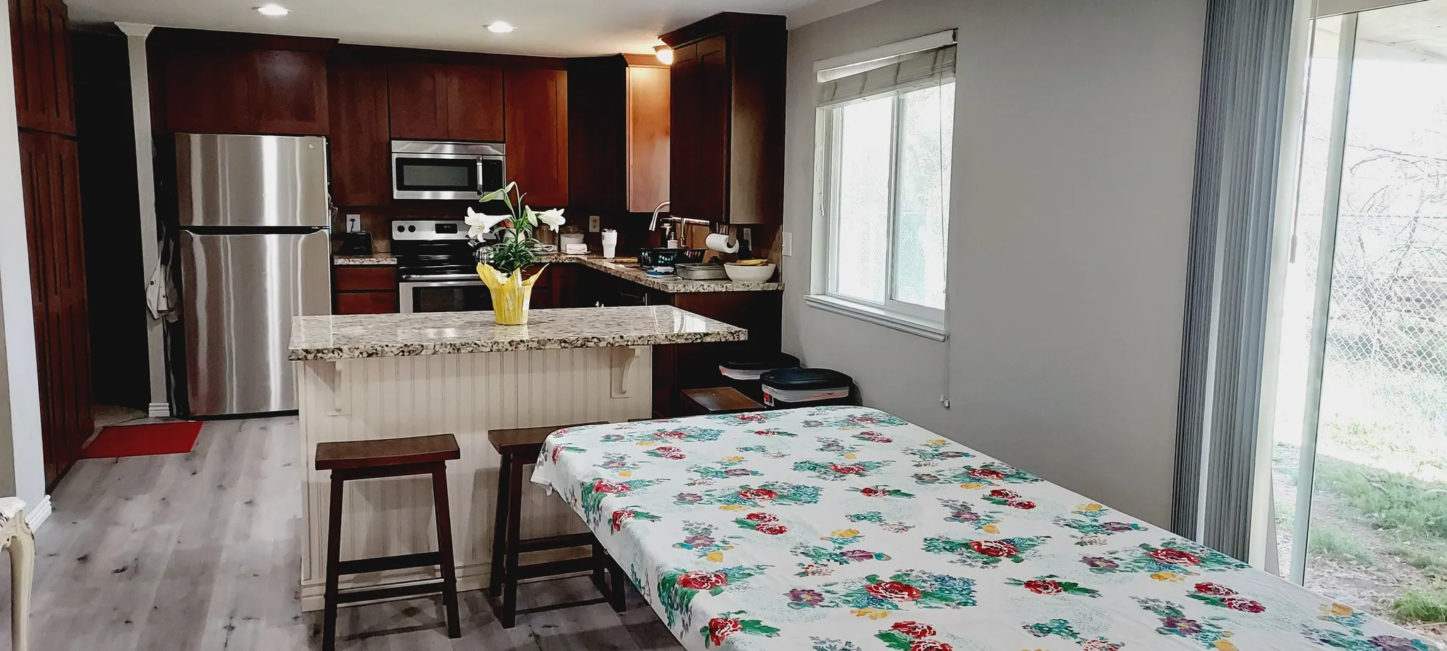 Kitchen with stainless steel appliances, a breakfast bar, light stone countertops, light wood finished floors, and a center island