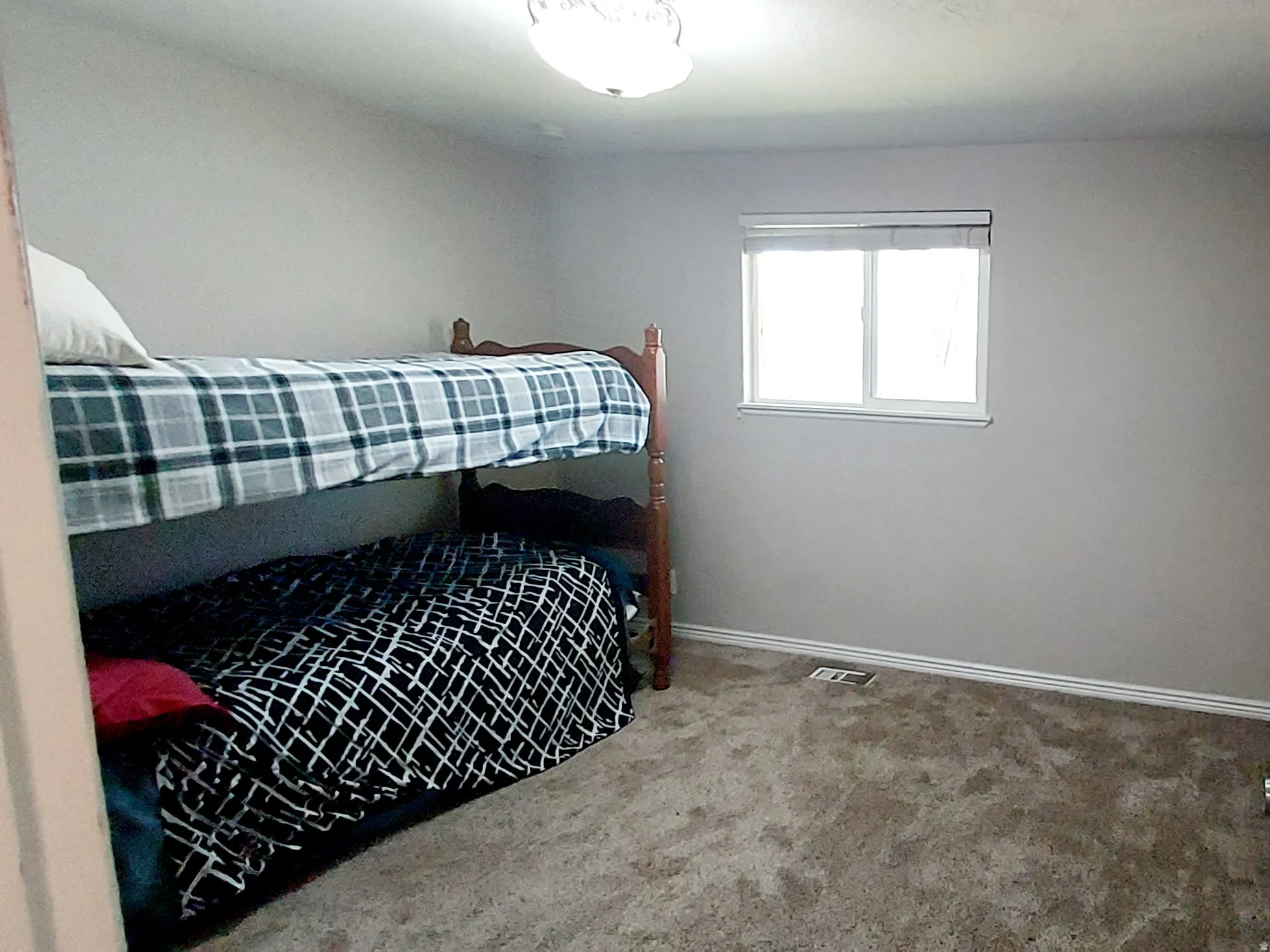 Bedroom featuring light gray wall paint, a single window with white trim, and a ceiling-mounted light fixture