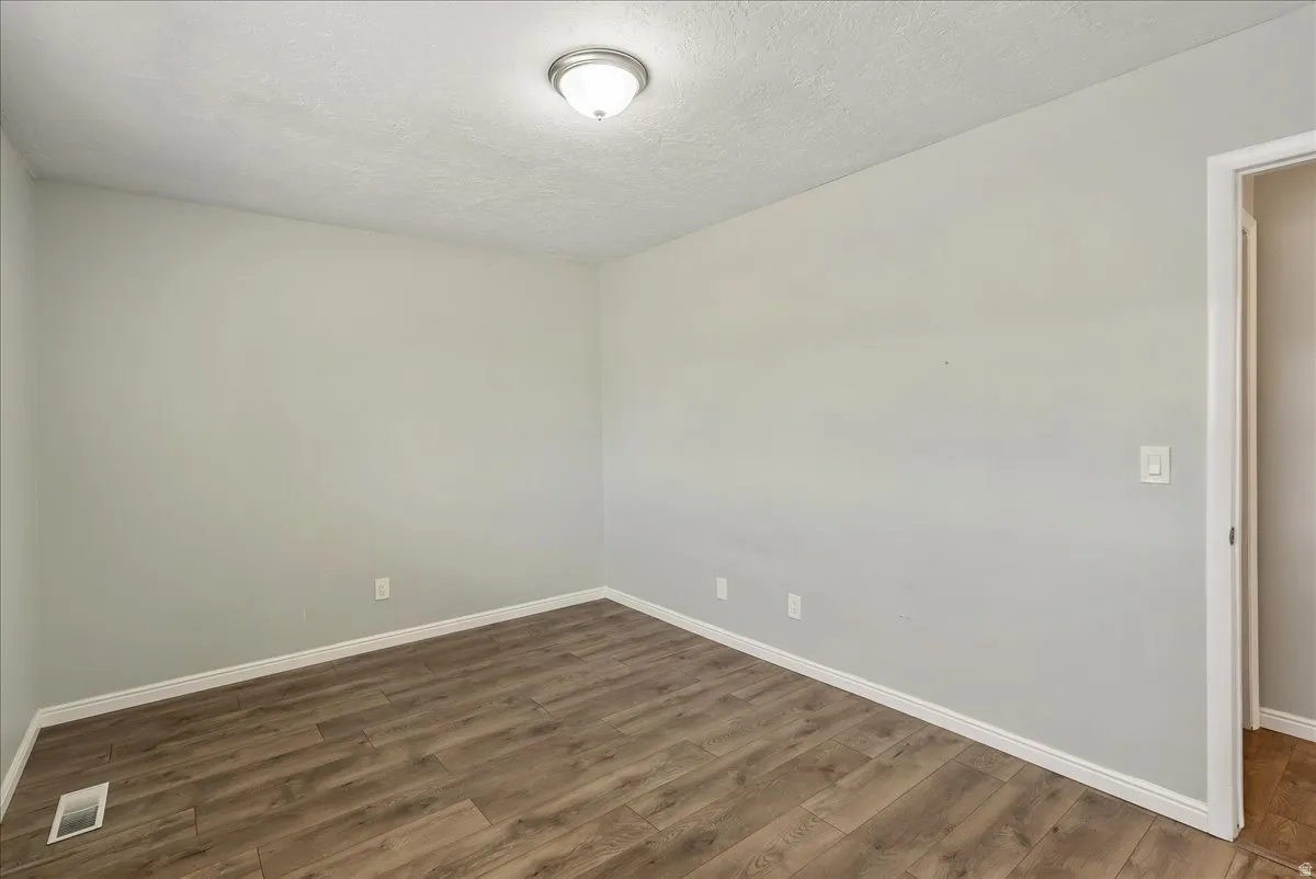 Neutral-toned interior featuring wood-finish flooring, white baseboards, and a flush mount ceiling light