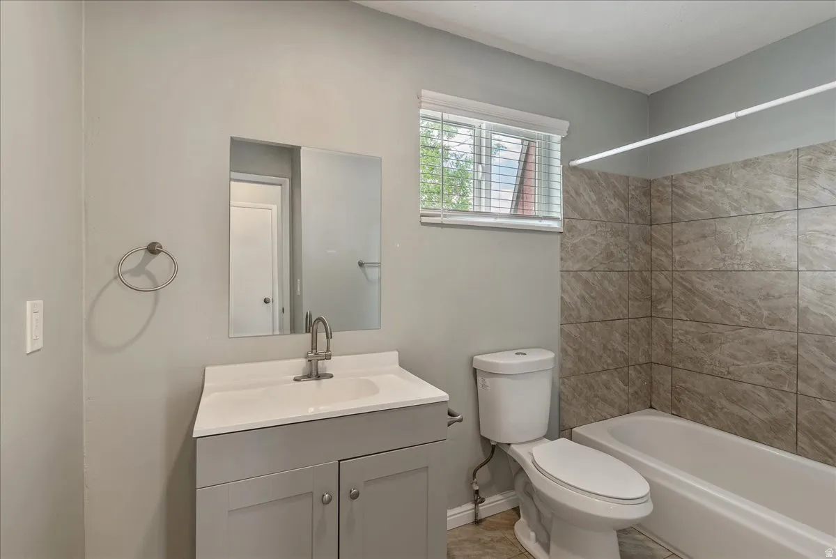 Full bathroom featuring a single vanity with storage, a white countertop, and a brushed nickel faucet