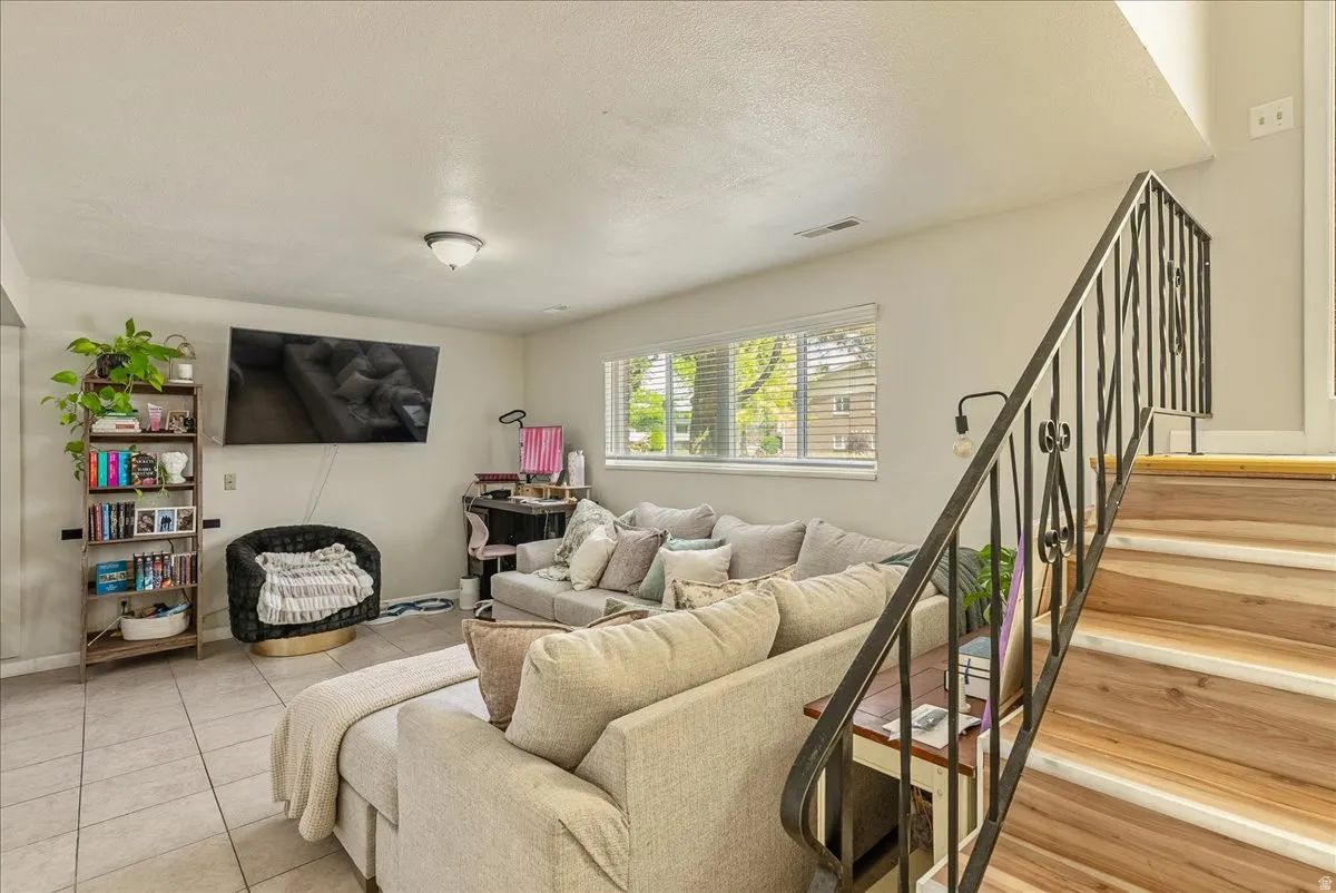 Finished living space featuring tile flooring, a large window with blinds, and recessed lighting