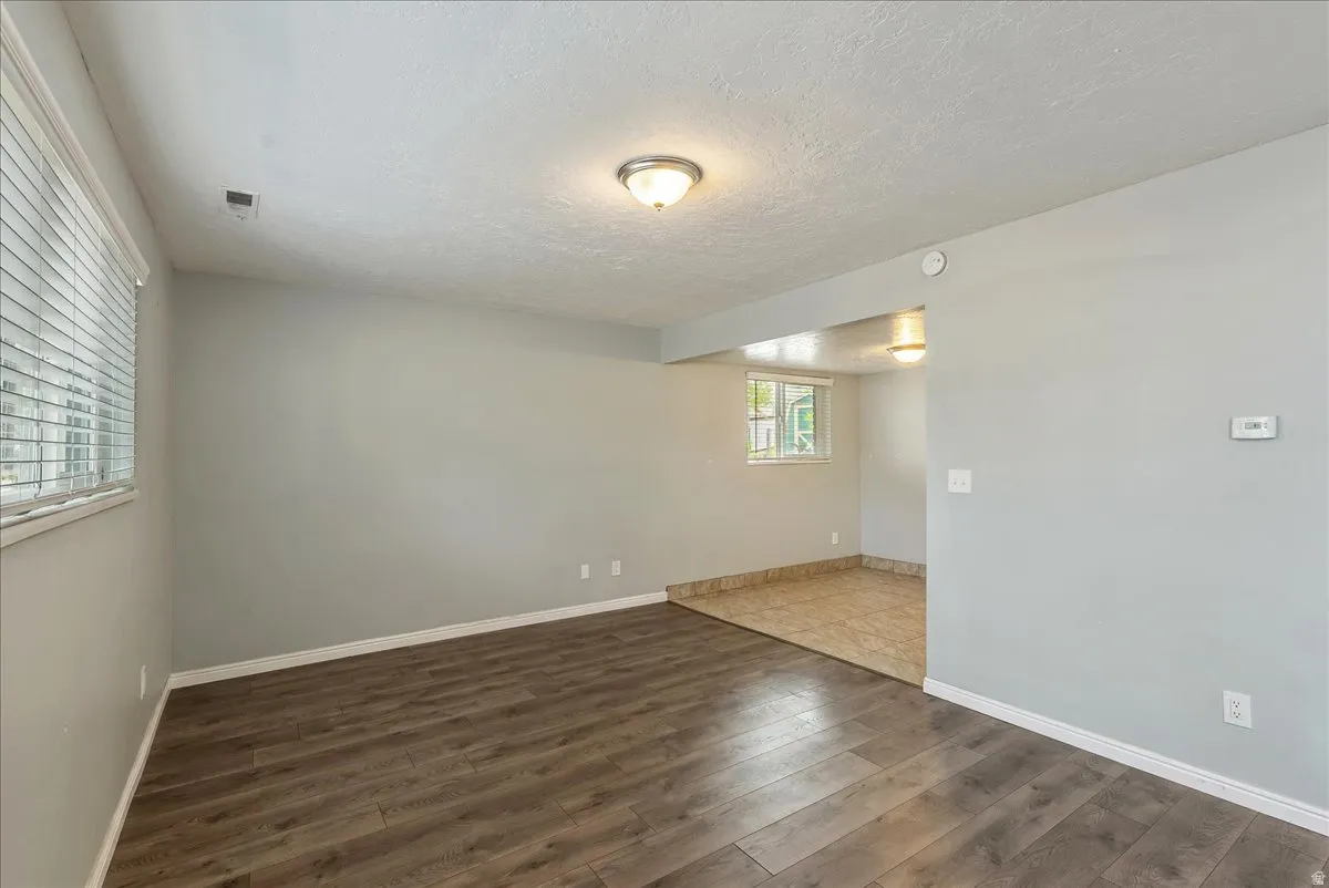 Spacious room featuring wood-finish flooring, light gray walls, and white baseboards