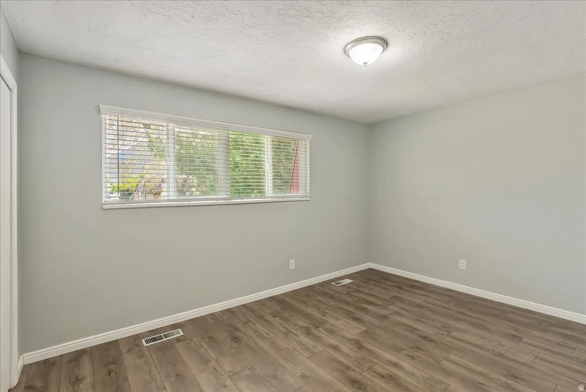Bright room featuring wood-finish flooring, light gray walls, white baseboards, and a contemporary ceiling light fixture