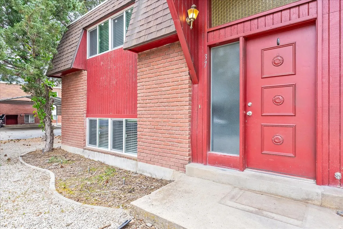 Entryway featuring a red paneled door with decorative medallions, an adjacent frosted glass sidelight, and an illuminated wall sconce