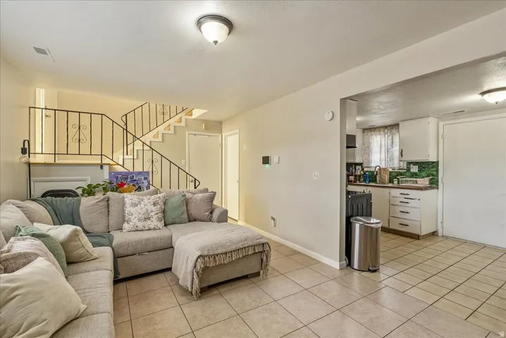 Open concept living space featuring tile flooring and a staircase with decorative wrought iron railings