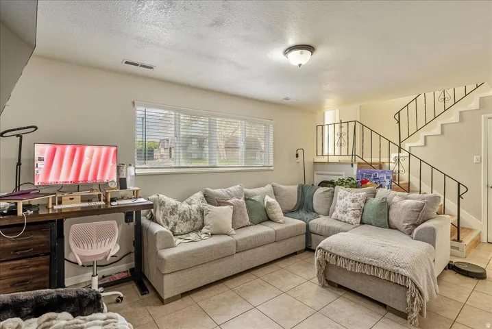Neutral-toned tile flooring complements light-colored walls and a window with horizontal blinds
