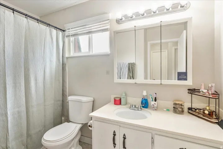 Bathroom featuring a white vanity with an integrated sink, a medicine cabinet with mirrored doors, and a multi-bulb light fixture