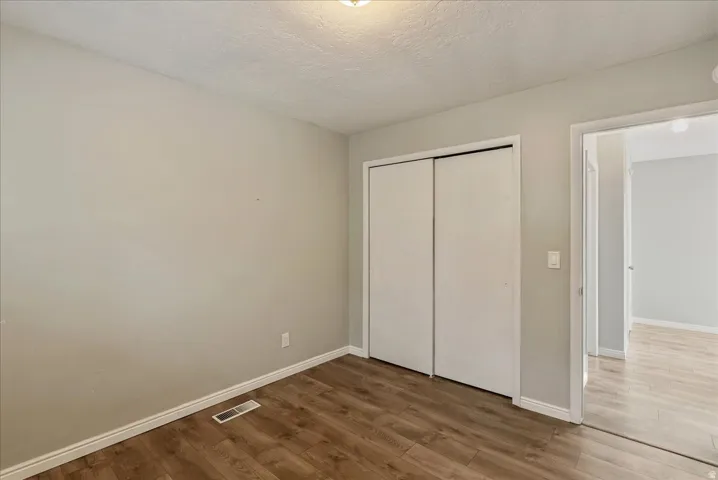 Room featuring wood-finish flooring, light grey painted walls, and white baseboards