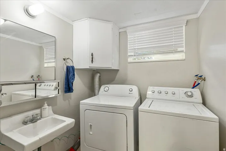 Dedicated laundry area featuring a wall-mounted sink, a mirrored medicine cabinet, overhead cabinetry, and a window with blinds