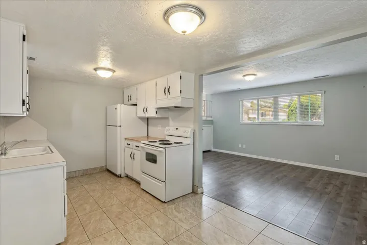 Kitchen featuring white cabinetry, a white refrigerator, a white electric range, and tile flooring