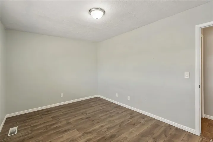 Neutral-toned interior featuring wood-finish flooring, white baseboards, and a flush mount ceiling light