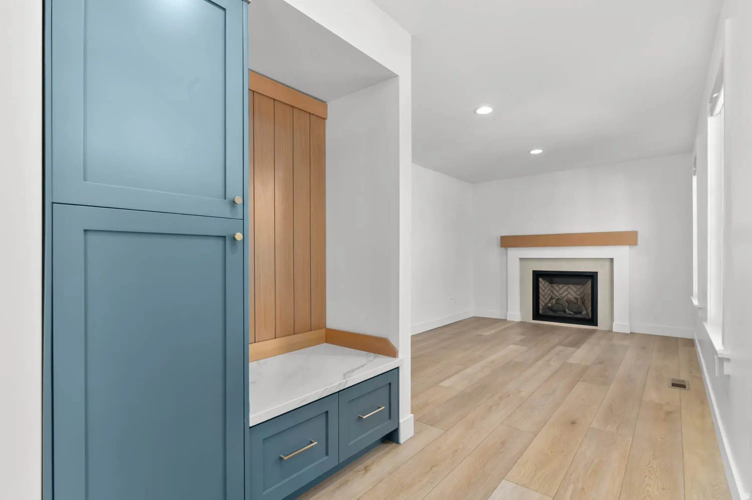 Built-in storage cabinetry with blue finish, complemented by a wood-paneled bench with a stone-finish top and integrated drawers
