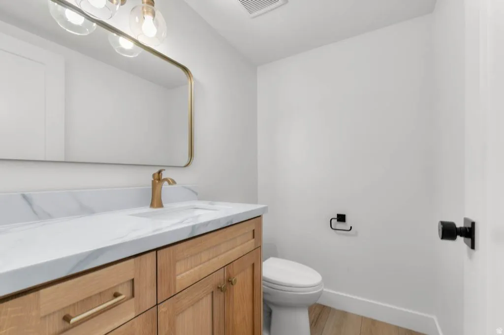 Bathroom featuring a light wood-finish vanity with gold-tone hardware, a white countertop with subtle veining, and a gold-tone faucet