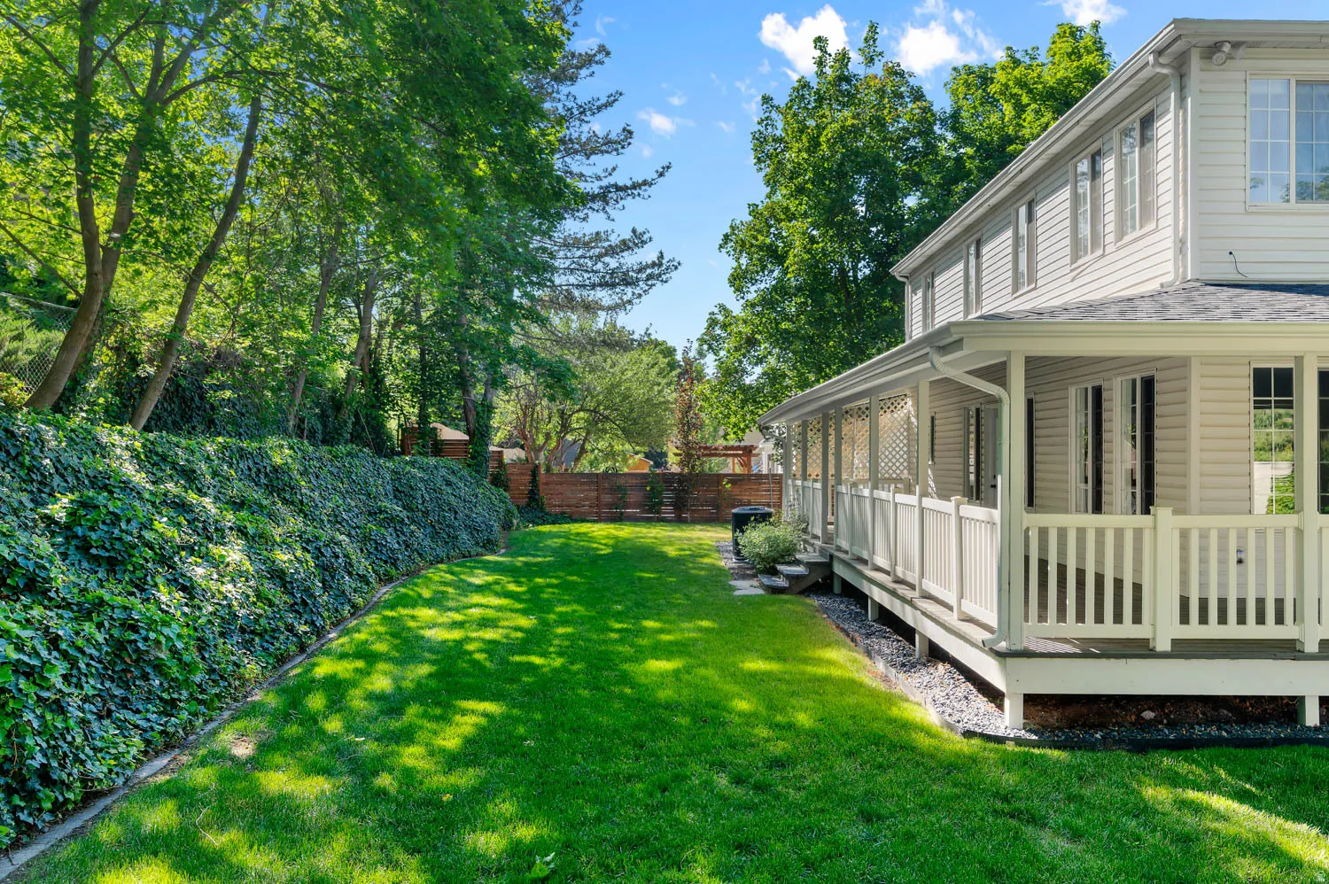Expansive green lawn bordering a covered porch with white railing