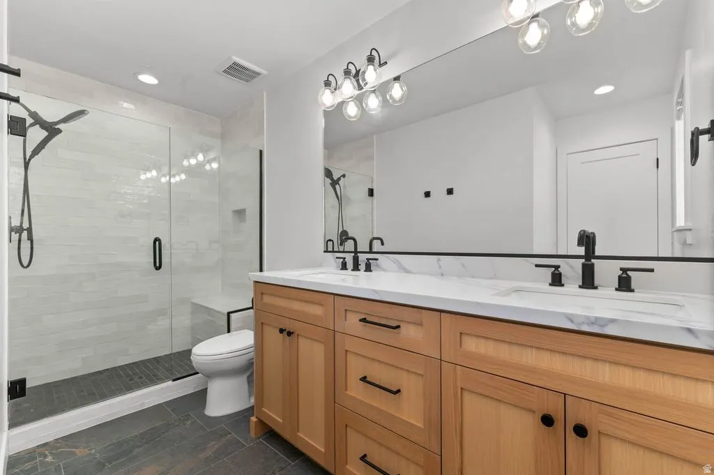 Double vanity featuring a white countertop with integrated sinks, black fixtures, and light wood cabinetry