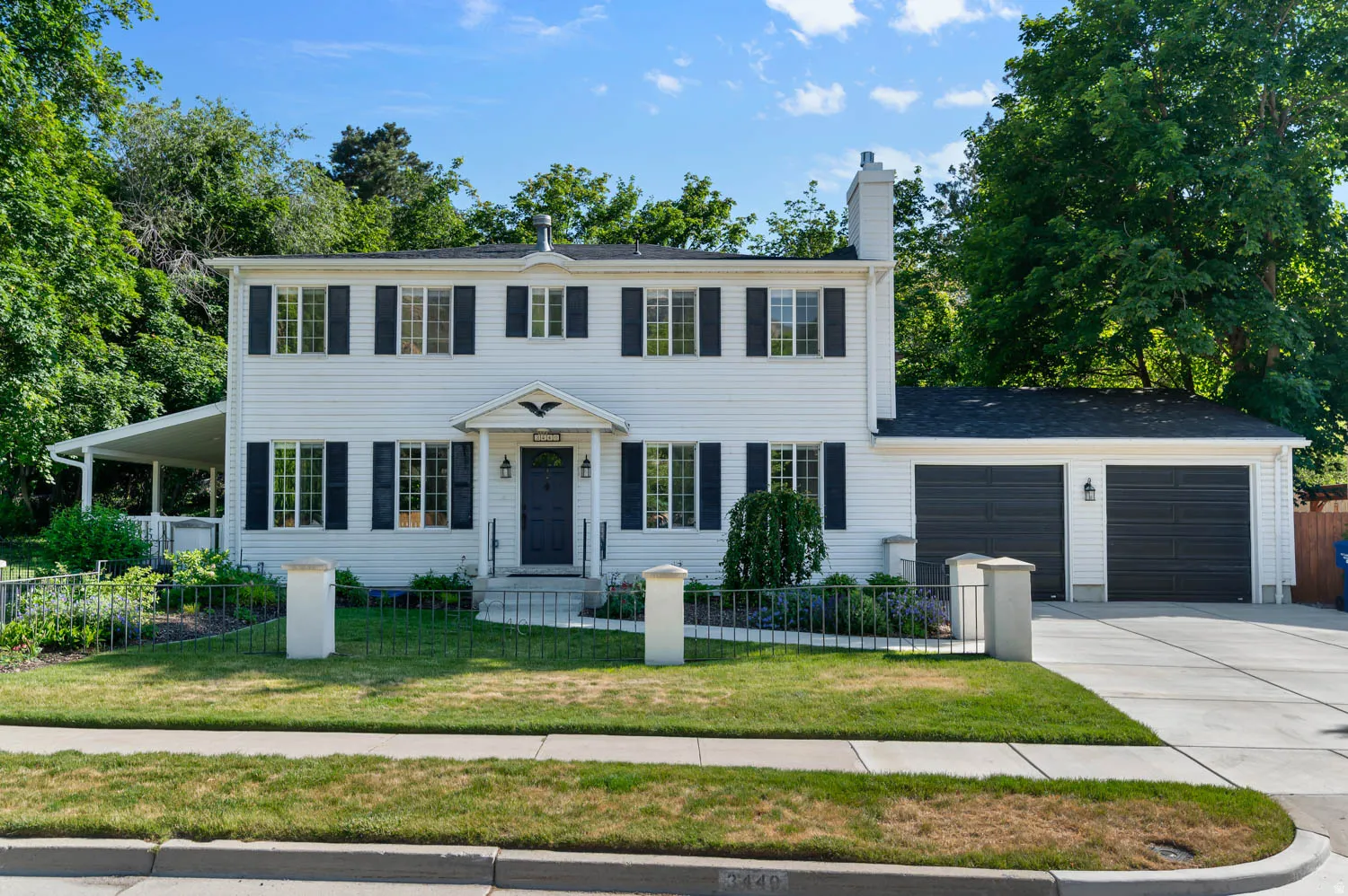 Colonial-style residence featuring a white facade, dark shutters, and a covered porch