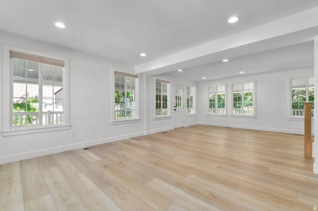 Expansive room featuring wood-finish flooring and recessed lighting