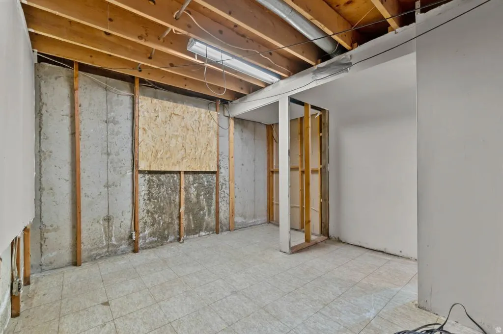 Unfinished basement offering exposed ceiling joists, concrete foundation walls, existing wall framing, and tiled flooring