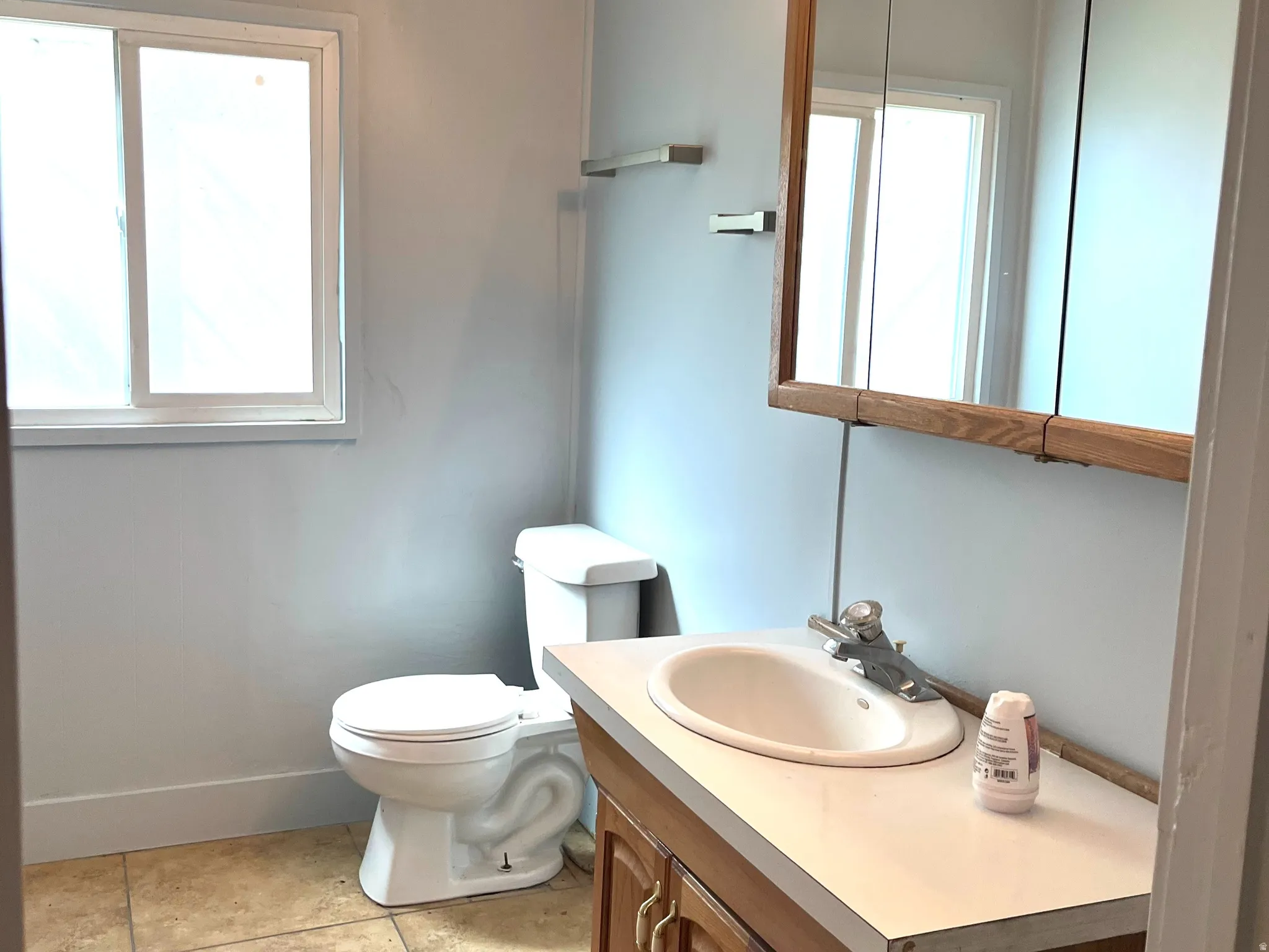 Bathroom featuring a wood-finish vanity with an integrated sink and laminate countertop
