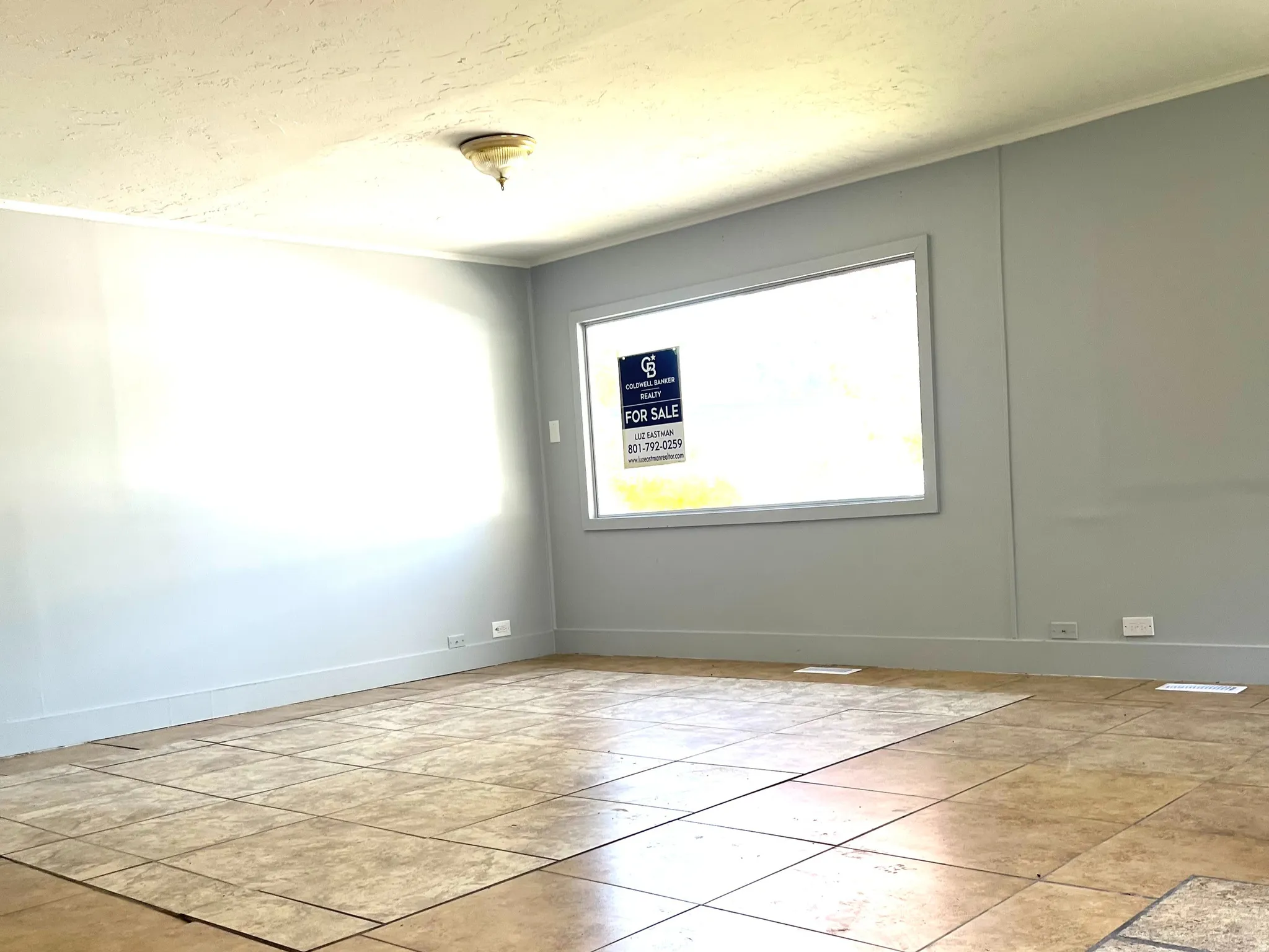 Interior space featuring a large window, neutral wall paint, and a tiled floor