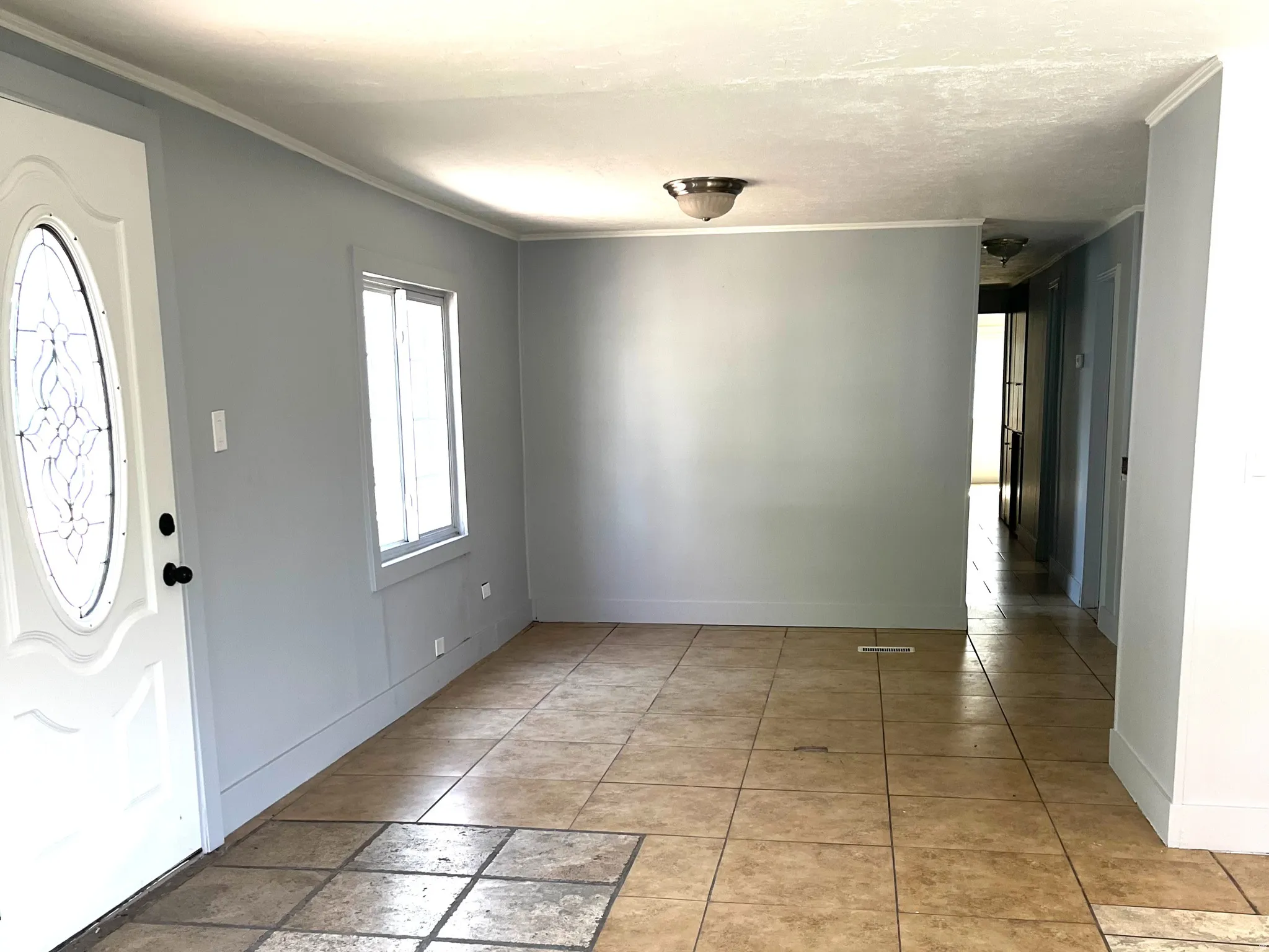 Living area with neutral wall color, crown molding, and tiled flooring