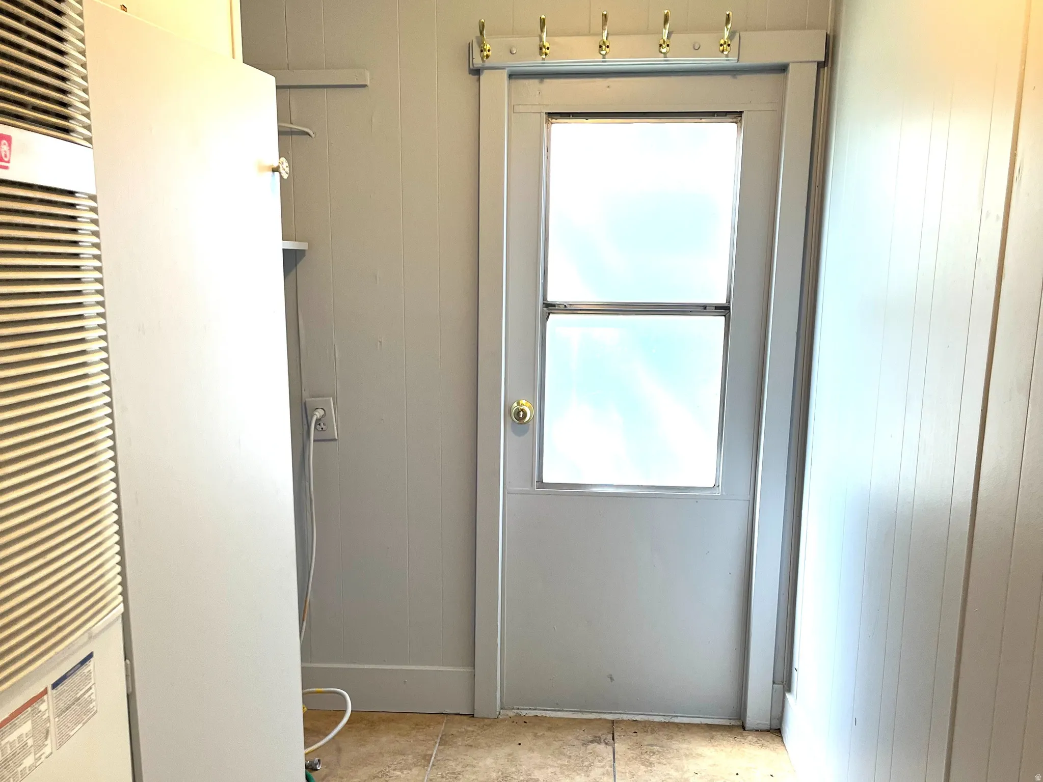 Utility area featuring light beige tile flooring and vertical paneling