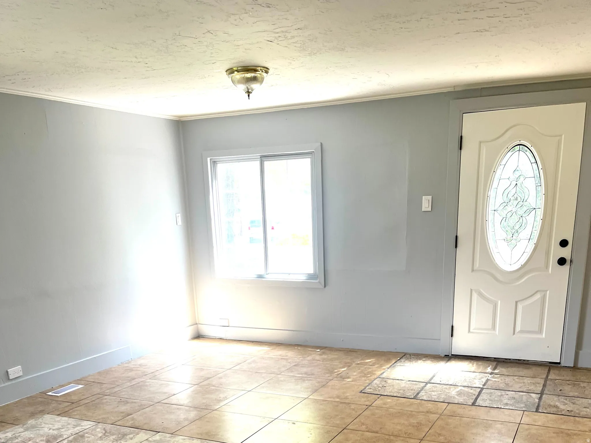 Interior space featuring a white entry door with an oval decorative glass insert, a single sliding window, a flush mount ceiling light fixture, and light-colored wall paint