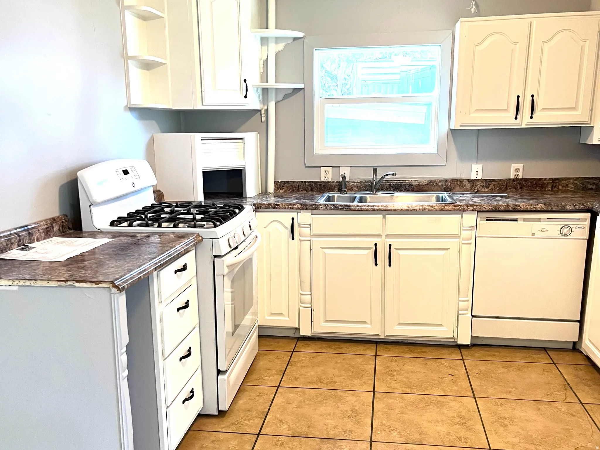 Kitchen featuring white cabinetry, a double basin sink, a gas range, and a dishwasher