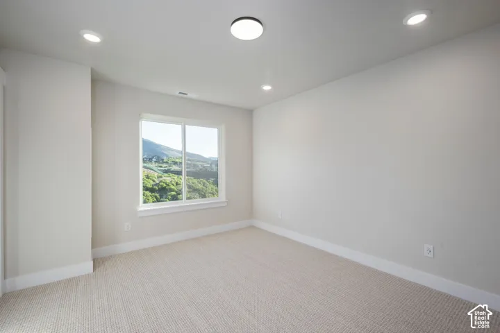 Bright room featuring a large window, recessed lighting, and neutral carpet flooring