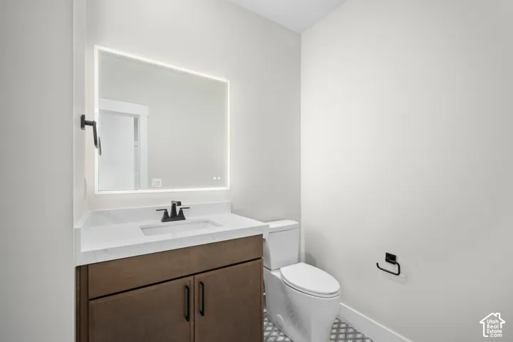 Modern vanity featuring a built-in sink, white stone-finish countertop, and rich wood-finish cabinetry with matte black hardware