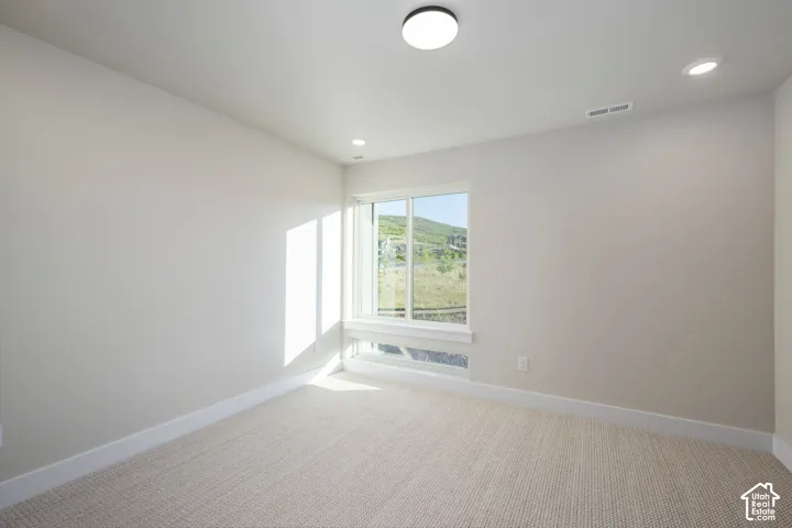 Room featuring a large window, neutral carpeting, recessed lighting, and a flush-mount ceiling fixture