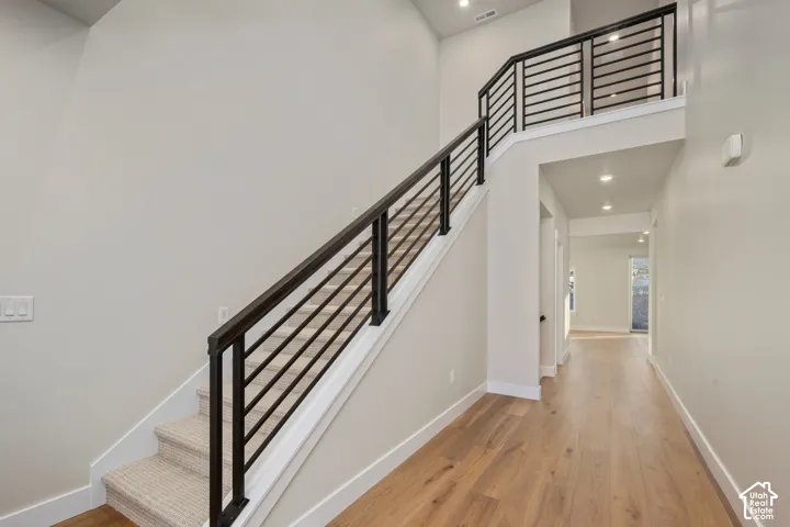 Two-story entry foyer featuring a contemporary staircase with black horizontal bar railings and carpeted treads