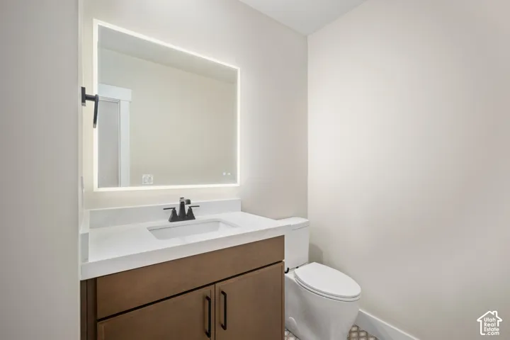 Bathroom featuring a wood-finish vanity with a white countertop, an integrated rectangular sink, and a matte black faucet
