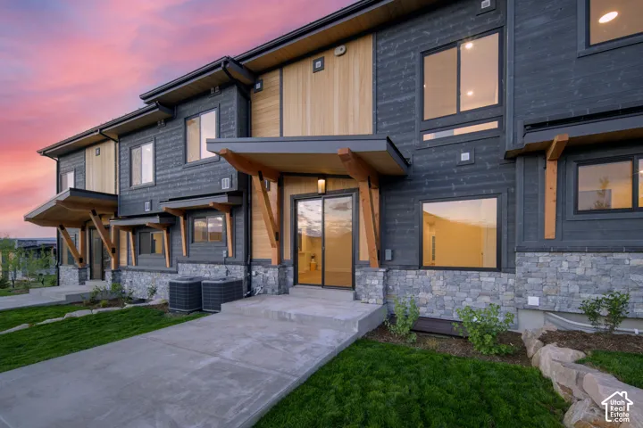 Contemporary multi-level exterior featuring dark horizontal siding, natural wood accents, and a stacked stone foundation
