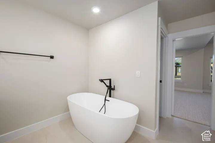 Freestanding soaking tub with a matte black floor-mounted faucet