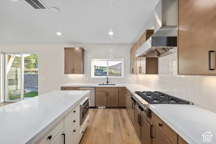 Modern kitchen featuring light wood-finish cabinetry, white countertops, and a white tiled backsplash