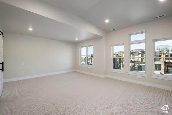 Spacious room featuring neutral carpeting and multiple windows
