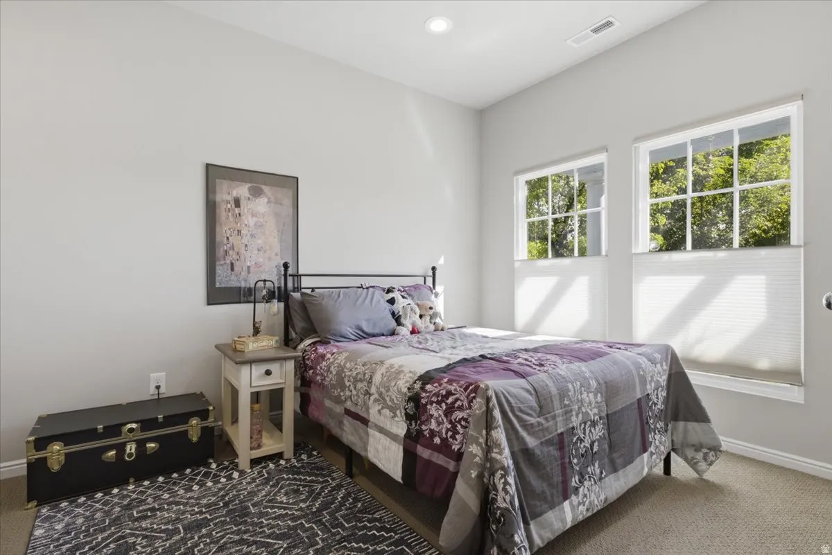 Carpeted room featuring a neutral color palette, two paneled windows with cellular shades, and recessed lighting