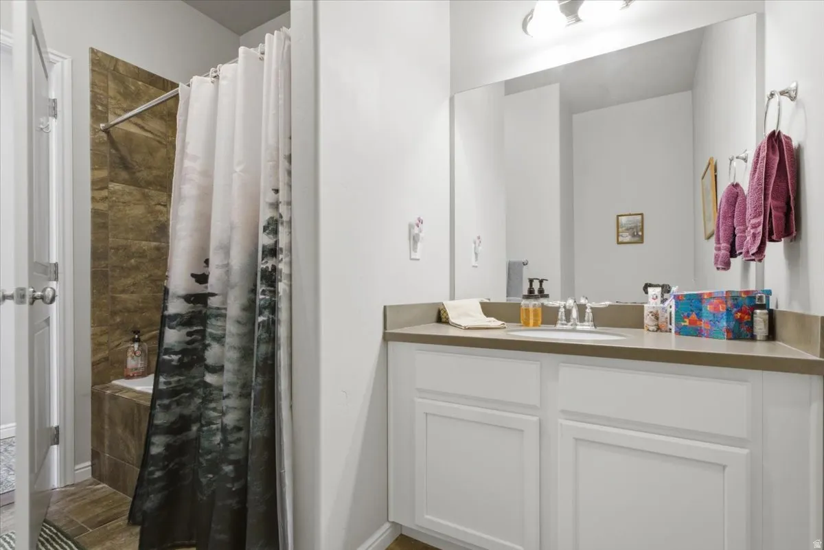 Bathroom featuring a vanity with white cabinetry, a single sink, and a light-toned countertop