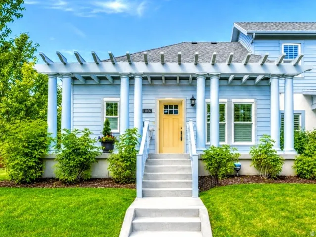Light blue siding exterior featuring a prominent pergola over the entryway