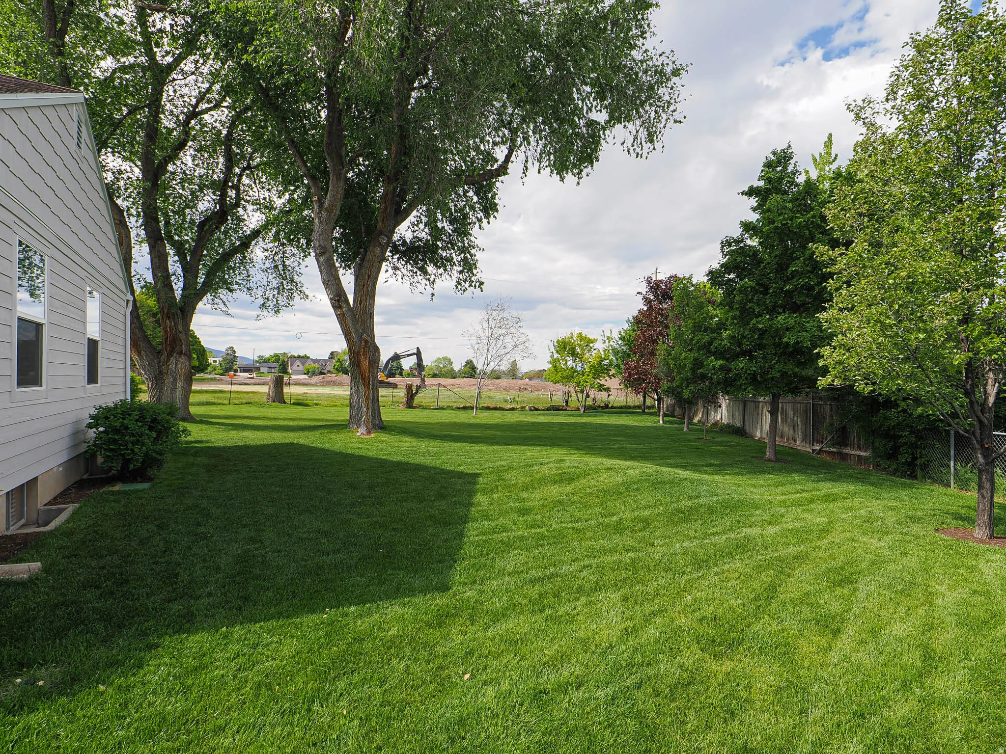 Expansive green lawn with mature trees and perimeter fencing